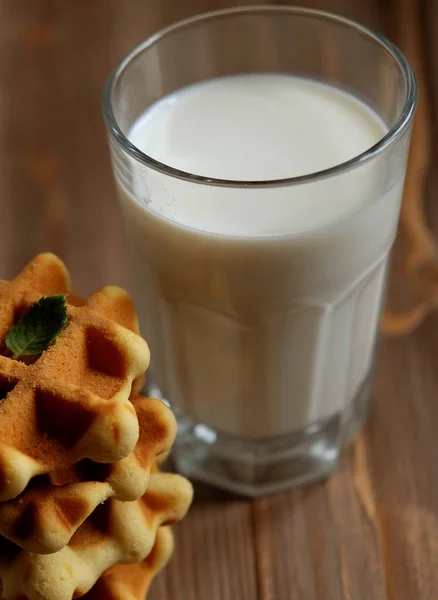 Gofres y vaso con leche. Desayuno por la mañana sobre fondo de madera — Foto de Stock
