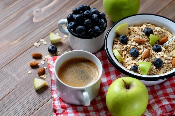 Ein gesundes Frühstück ist ein guter Start in einen neuen Tag. Haferbrei, Kaffee, Apfel, Beeren und Nüsse auf einem Holztisch. Ansicht von oben. — Stockfoto