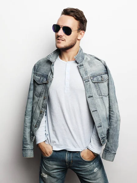Stilig man i smart slitage, bär mode solglasögon mot vit bakgrund — Stockfoto