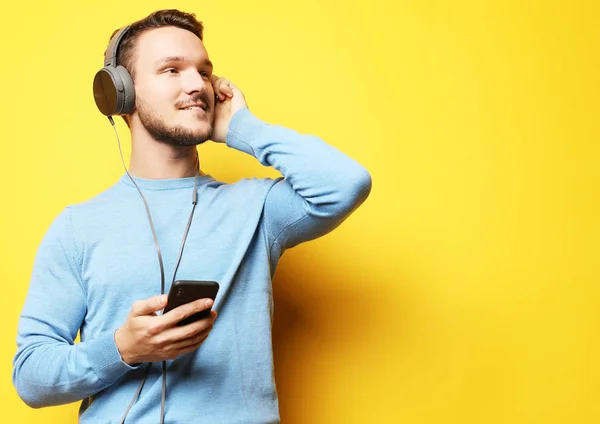 Knappe man likken aan muziek over gele achtergrond — Stockfoto