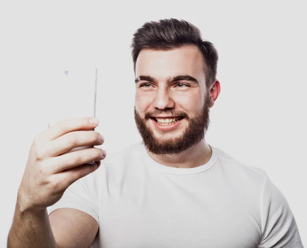Close up portrait of a cheerful bearded man taking selfie over white background — Stock Photo, Image