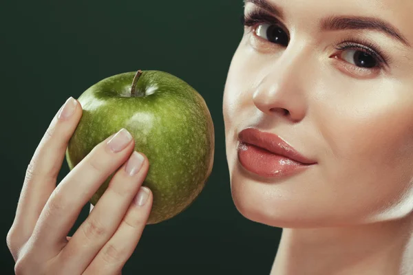 Head shot of woman holding green apple against green background — Stock Photo, Image