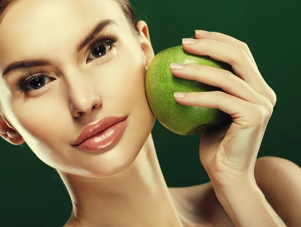 Head shot of woman holding green apple against green background — Stock Photo, Image