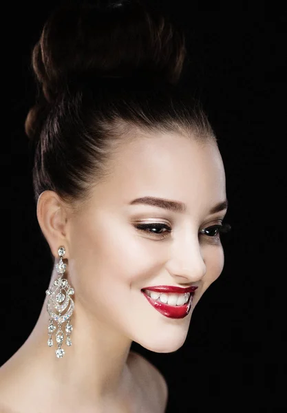 Belle femme brune avec maquillage lumineux et boucles d'oreilles bijoux souriant gros plan. lèvres et ongles rouges, maquillage du soir, look luxueux . — Photo