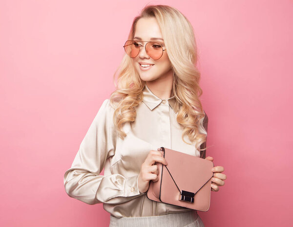 Beautiful blond woman in a blouse and pants wearing glasses, holding handbag