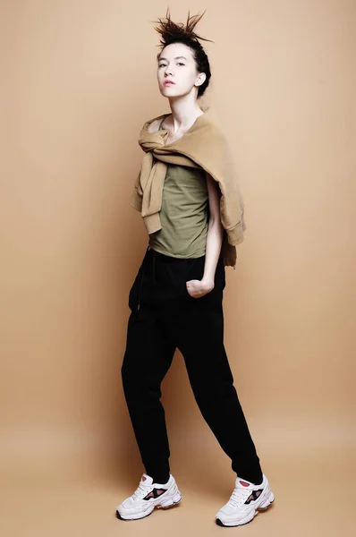 Joven modelo morena posando en estudio, fondo beige — Foto de Stock