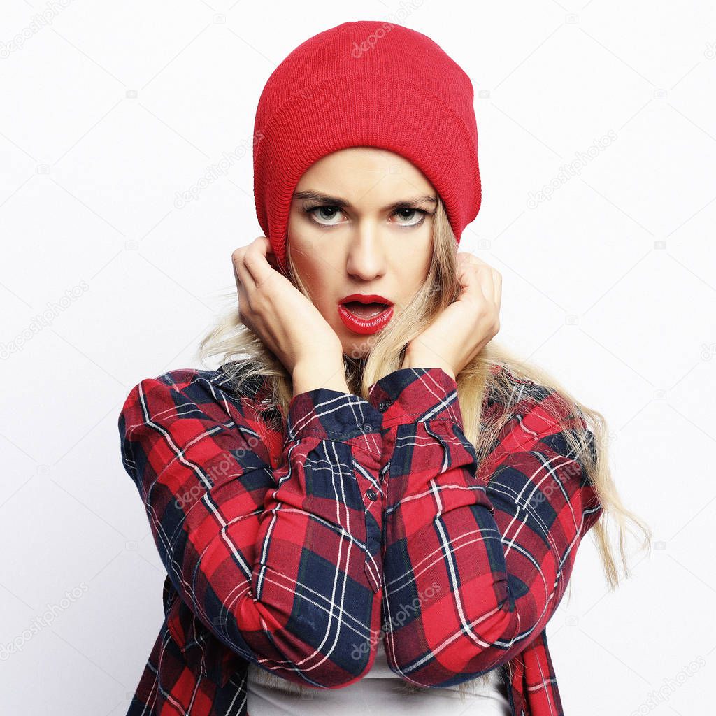 Lifestyle concept. young hipster blonde woman with bright sexy make up wearing stylish urban plaid shirt and red hat, white background.