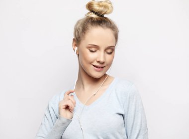 Kulaklıklı, beyaz arka planda müzik dinleyen güzel genç bir kadın.