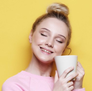yaşam tarzı, gıda ve insanlar kavramı: genç güzel kadın sarı arka plan üzerinde kahve içme