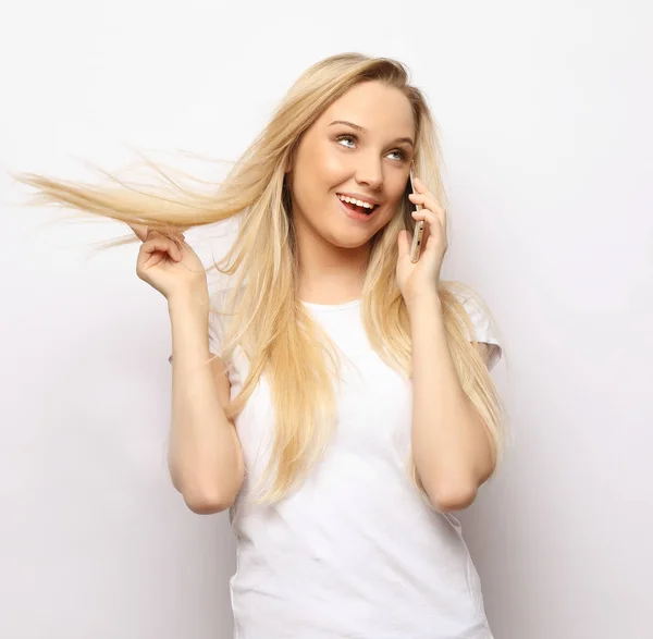 Lifestyle and people concept - Beautiful happy blonde woman is talking on the phone and touching her hair — Stock Photo, Image