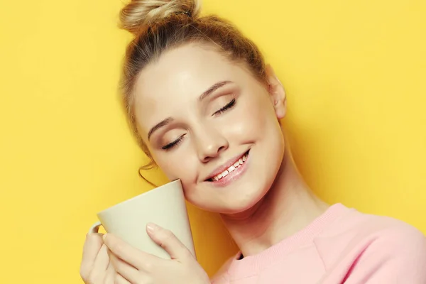 Спосіб життя, їжа і концепція людей: молода красива жінка п'є каву на жовтому фоні — стокове фото