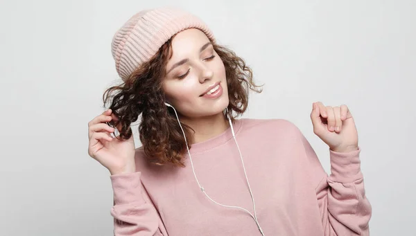 Lifestyle en mensen concept: Mooie jonge krullende vrouw in hoofdtelefoon luisteren naar muziek glimlachen met gesloten ogen — Stockfoto