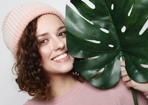 Mladá krásná žena nosí růžové ležérní oblečení, držící list monstera — Stock fotografie