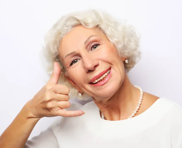 Lifestyle and people concept: Aged woman showing call center sign. Portrait of handsome expressive grandmother. Close up — Stock Photo, Image