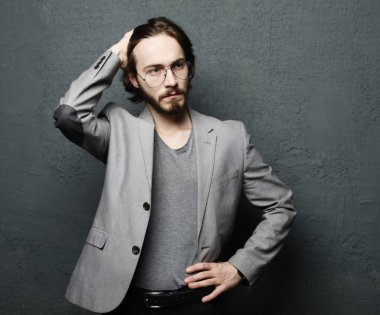 Gri duvar arkasında poz veren genç yakışıklı adam.