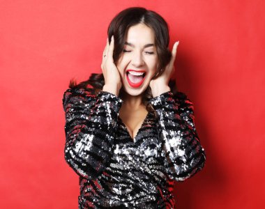 Kırmızı arka planda ağzı açık, gece elbisesi giymiş sürpriz bir kadın.