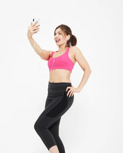 Porträtt av en leende fitness kvinna med smartphone. Selfie tid. — Stockfoto