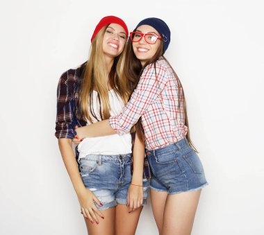Yaşam tarzı, duygu ve insan konsepti: iki genç kız arkadaş bir arada duruyor ve eğleniyorlar. Hipster tarzı.