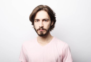 Beyaz arka planda poz veren sakallı genç bir adamın portresi.