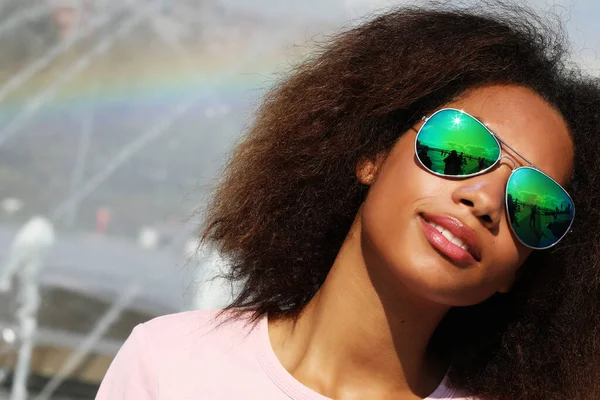 Jong Afrikaans amerikaans meisje in zonnebril, poseren buiten, gekleed casul, met kort volumineus haar. — Stockfoto