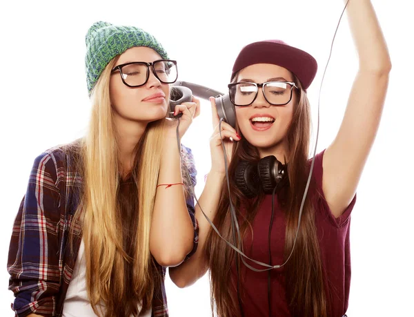 Livsstil, känslor och människor koncept: två unga flickvänner står tillsammans och lyssnar på musik. — Stockfoto