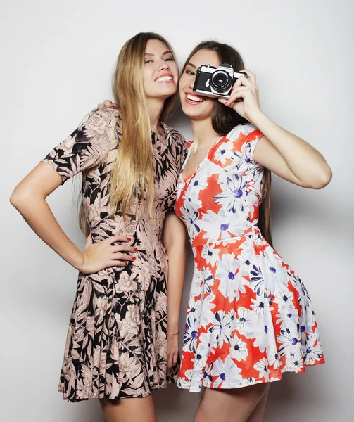 Fashion and people concept - two stylish sexy girls best friends wearing dress with camera — Stock Photo, Image