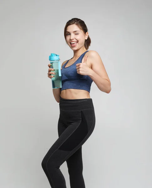 Spor, insanlar ve fitness konsepti: spor giyen genç bir kadın beyaz arka plan üzerinde su bulunan bir şişe tutuyor — Stok fotoğraf
