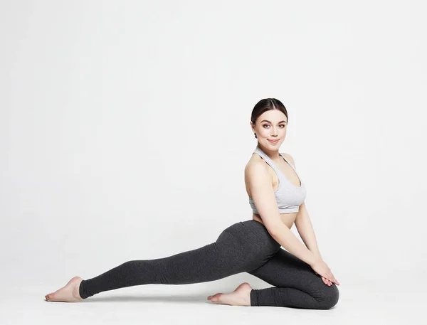 Mujer joven practicando yoga, haciendo ejercicio, usando ropa deportiva, sesión de estudio sobre fondo blanco — Foto de Stock