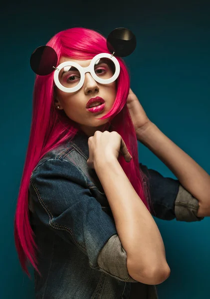 Fashion model with pink hair and big sunglasses over blue background — Stock Photo, Image