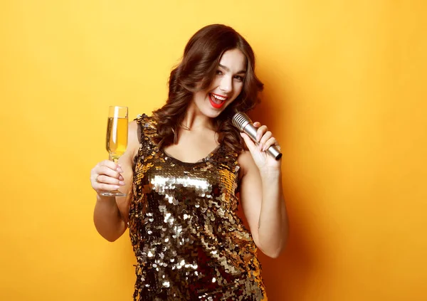 Siyah gece elbisesi giymiş bir kadın elinde bir bardak şampanya ve mikrofon tutuyordu.. — Stok fotoğraf
