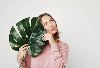 Yaşam tarzı, duygu ve insan konsepti - Güzel genç bir kadın büyük bir tropik çiçeğin yapraklarını tutuyor