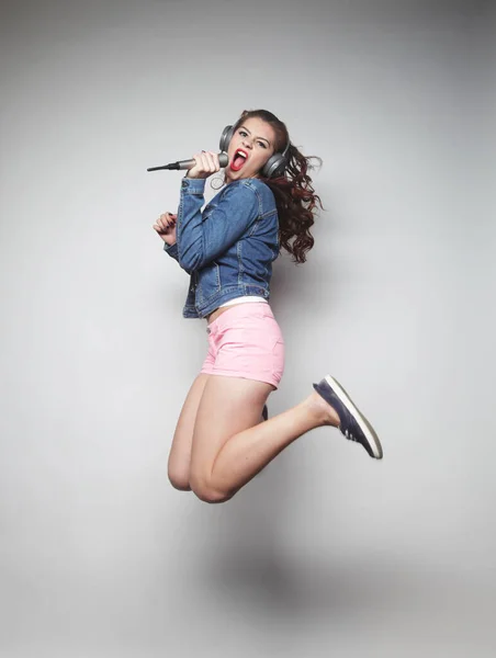 Mulher feliz com microfone pulando e cantando — Fotografia de Stock