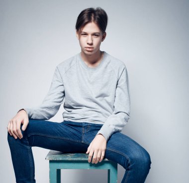 Moda adamı modeli sandalyede oturuyor.