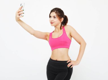 Akıllı telefonlu gülümseyen bir fitness kadınının portresi. Selfie zamanı..