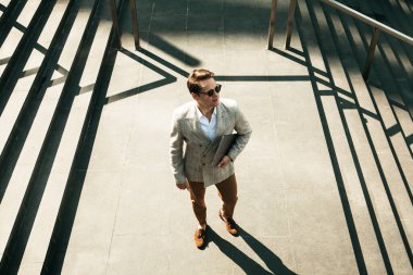 Yakışıklı, gülümseyen genç iş adamı şehirde vakit geçiriyor, merdivenlerde dizüstü bilgisayar kullanıyor.