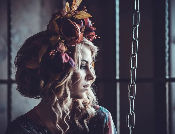 Urocza blondynka z kwiatowym wieńcem ubrana w elegancką sukienkę z kwiatowymi wzorami — Zdjęcie stockowe