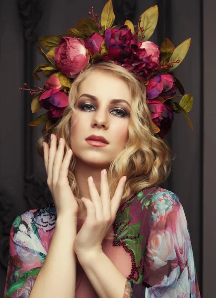 Charming blonde with a floral wreath dressed in a chic dress with floral patterns