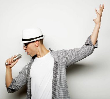 Genç adam mikrofonla şarkı söylüyor.