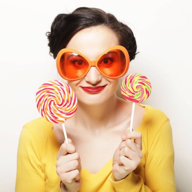 Büyük turuncu gözlüklü, elinde lolipop tutan komik bir kadın. Bir