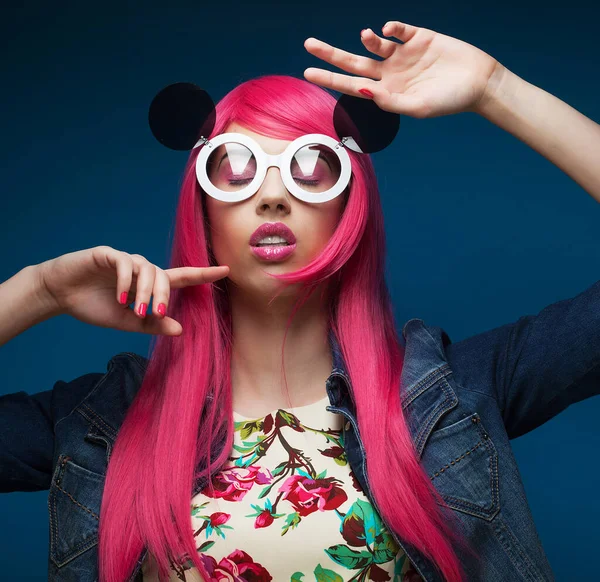 Fashion girl with pink hair and big sunglasses over blue background — Stock Photo, Image