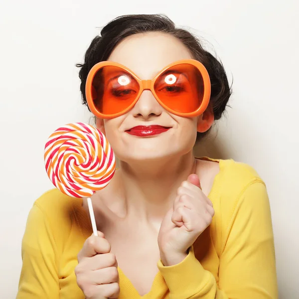 Mujer divertida con grandes gafas naranjas sosteniendo gran piruleta. Bir. — Foto de Stock