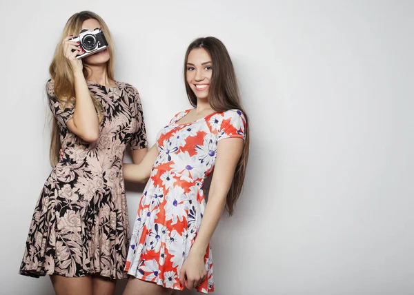 Yazlık elbiseler içindeki güzel genç kadınlar klasik bir kamera ile çekiliyor, beyaz arka plan. — Stok fotoğraf