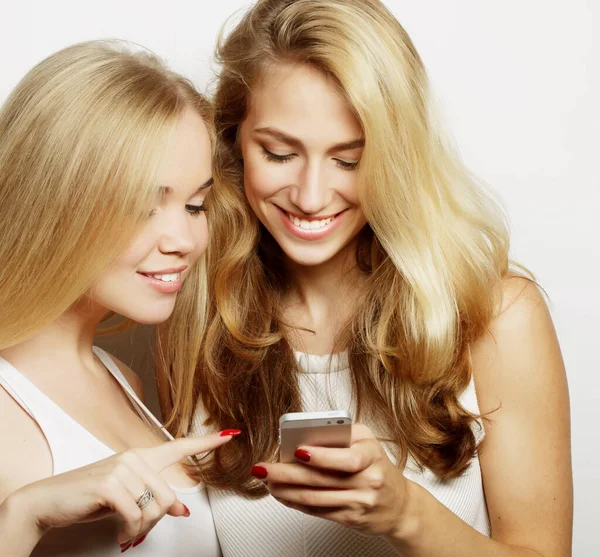 Dwie szczęśliwe przyjaciółki dzielą się mediami społecznościowymi w smartfonie — Zdjęcie stockowe