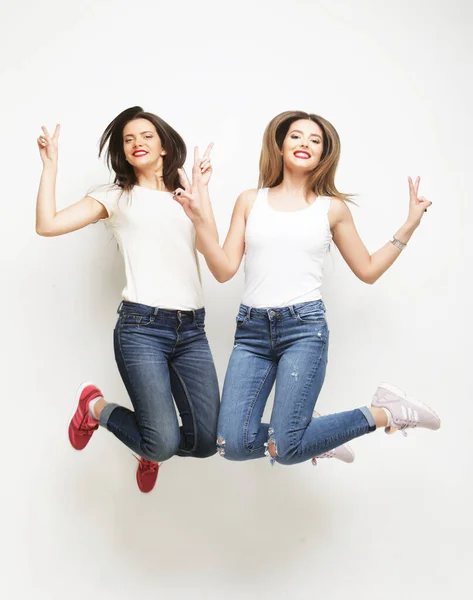 Lifestyle portrait of two young hipster girls best friends jump — Stock Photo, Image