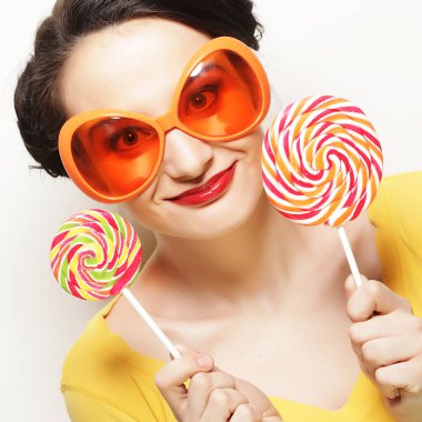 Büyük turuncu gözlüklü, elinde lolipop tutan komik bir kadın. Bir