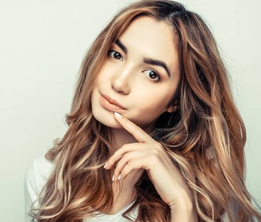 Beyaz tişörtlü, beyaz arka planda poz veren güzel bir kadın.