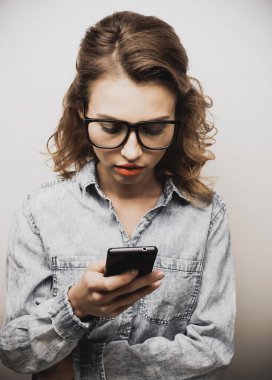 Akıllı telefon tutan kıvırcık saçlı tatlı bir kızın portresi.