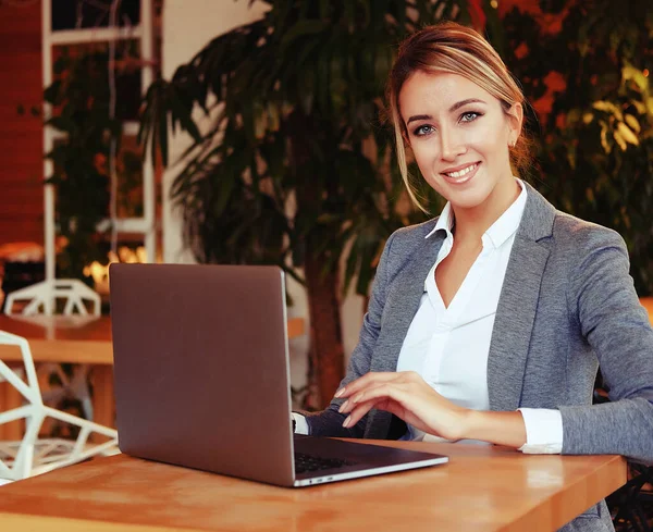 Trabajaba con una computadora portátil en la cafetería. Joven hermosa chica sitti — Foto de Stock