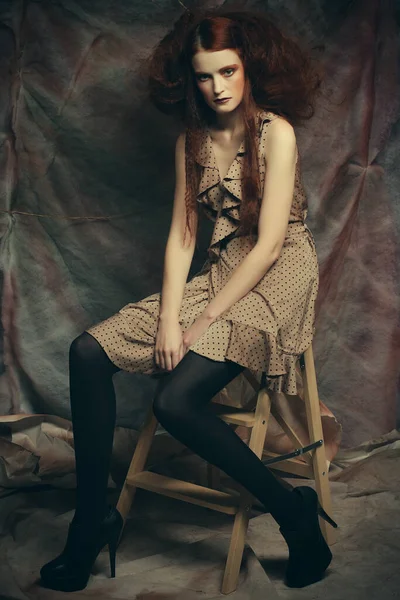 Modelo de moda jovem com criativo compõem sentado em um banquinho em — Fotografia de Stock