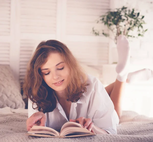 Koncepcja stylu życia i ludzi: młoda kobieta leżąca w łóżku podczas czytania — Zdjęcie stockowe